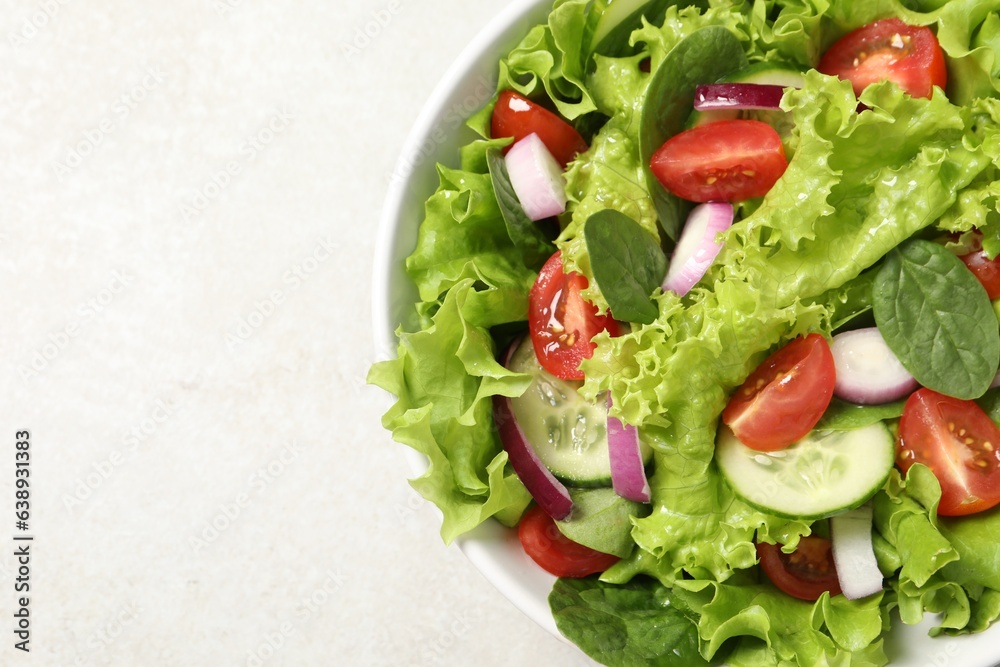 Delicious salad in bowl on light grey table, closeup. Space for text