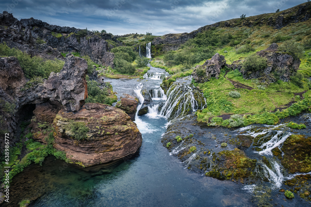 Gjain waterfall flowing in Pjorsardalur lush valley during summer at Iceland