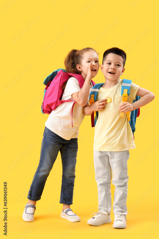 Cute little pupils with backpacks on yellow background