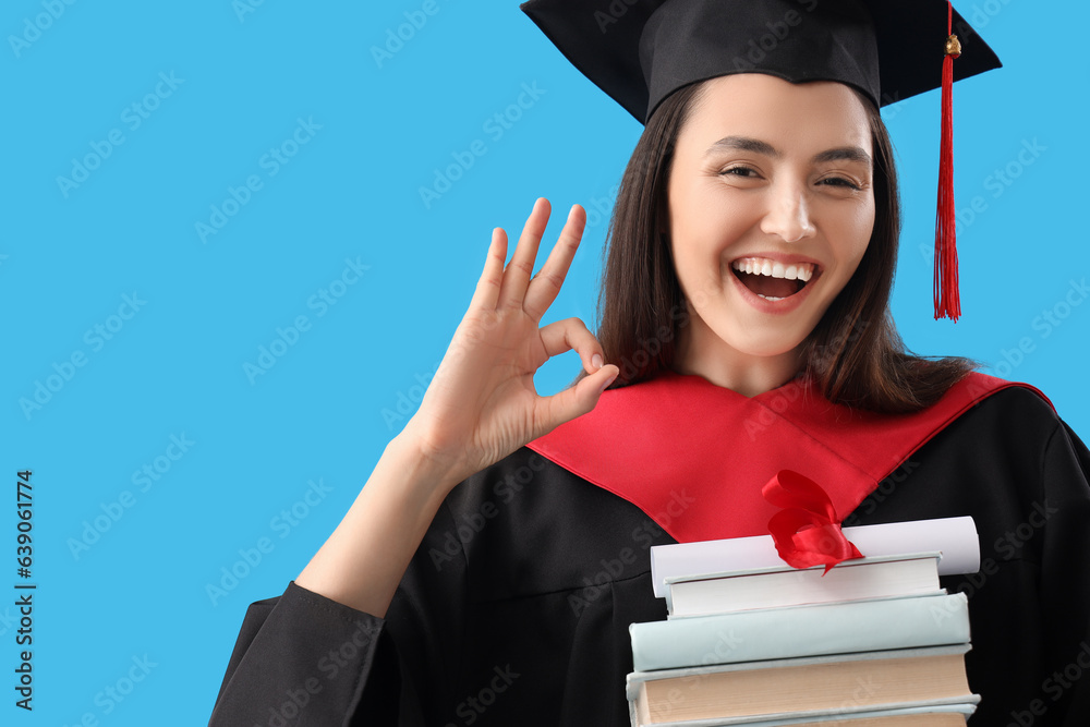 Female graduate student with diploma and books on blue background