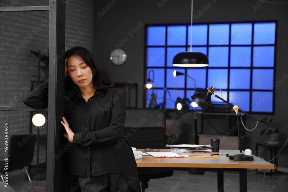 Tired Asian businesswoman in office at late evening