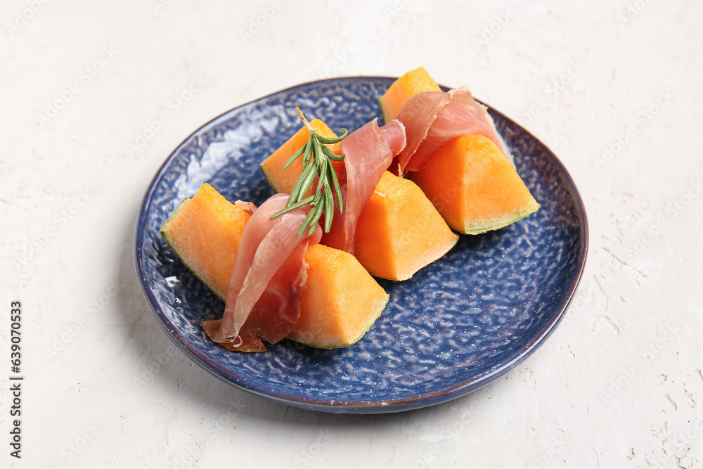 Plate with tasty melon and prosciutto on light background