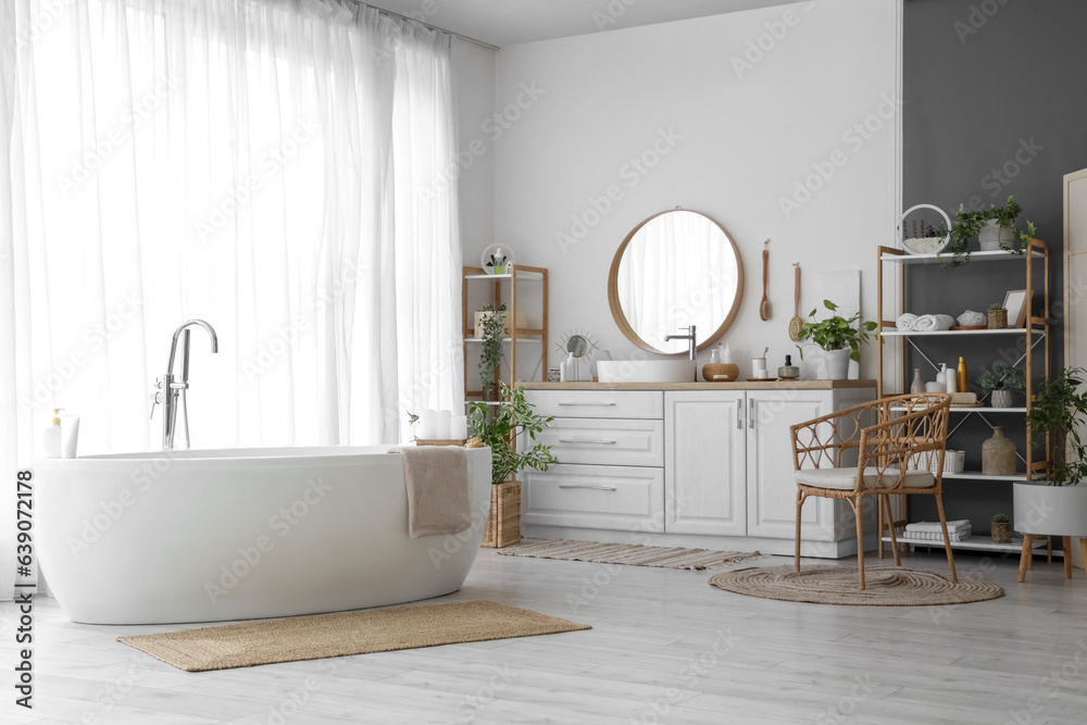 Interior of light bathroom with sink, accessories and bathtub