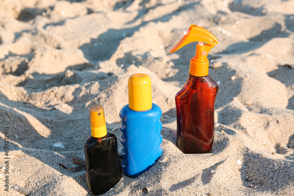 Bottles of sunscreen cream on sand at beach