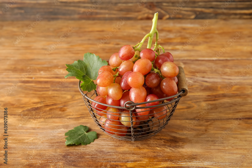 Basket with tasty ripe grapes on wooden background