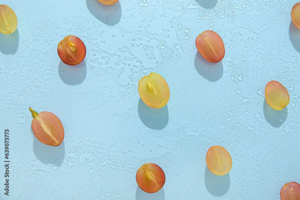 Halves of tasty ripe grapes in water on blue background