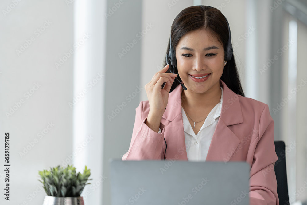 Asian businesswoman employee or executive using laptop computer and wearing headset video call expla