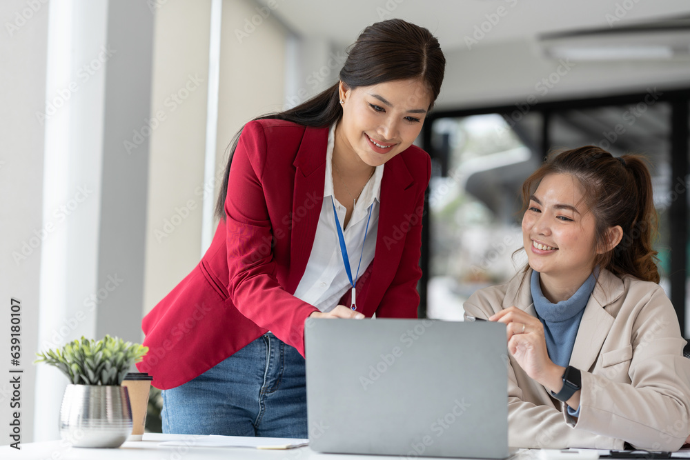 Two Asian businesswomen discuss working on a new project idea presentation. Calculate marketing plan