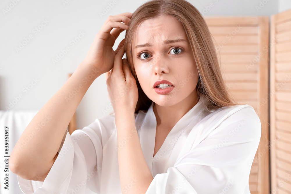 Shocked young woman with hair loss problem at home