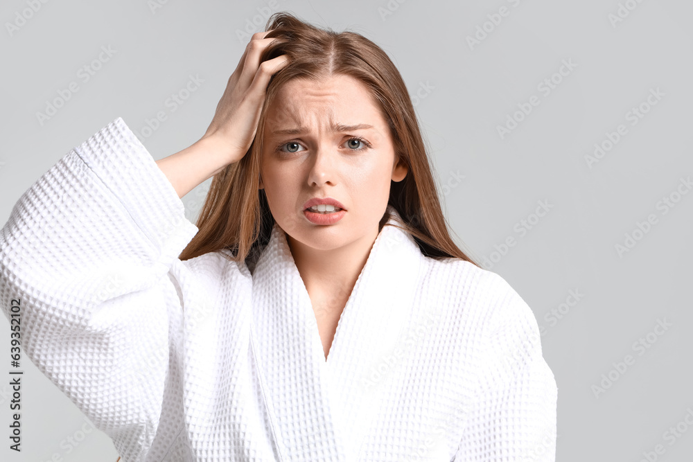 Worried young woman with hair loss  problem on light background