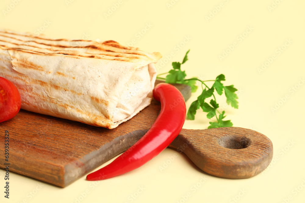 Board with tasty shawarma and ingredients on beige background