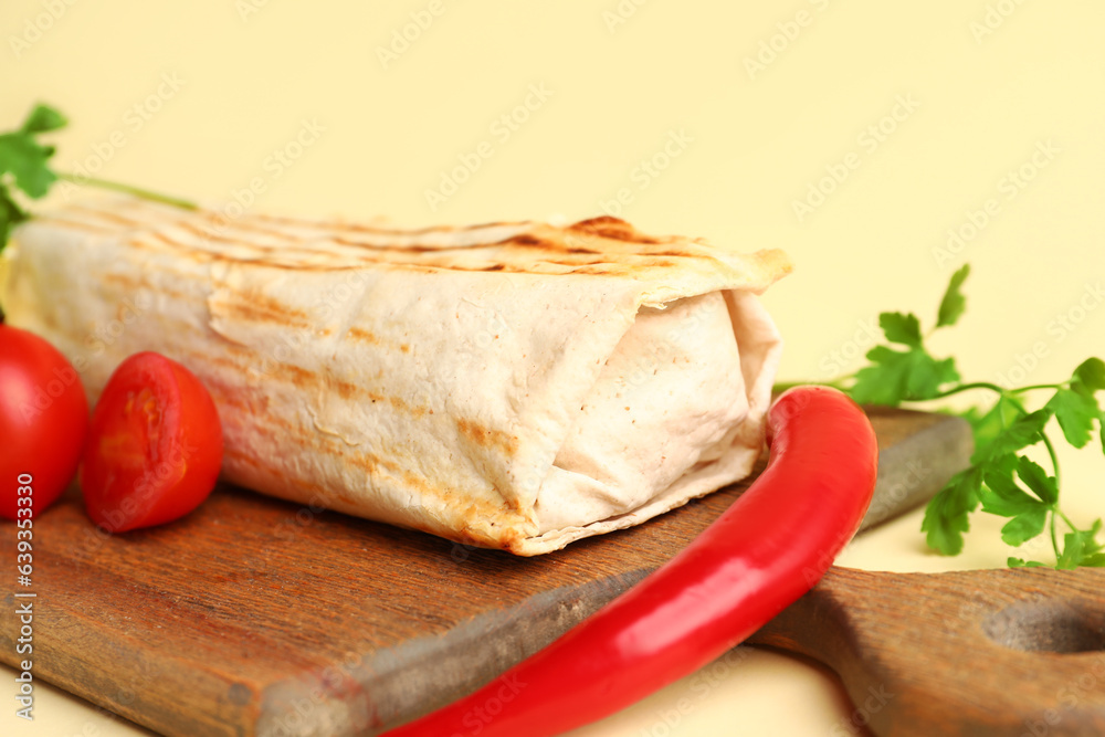 Board with tasty shawarma and ingredients on beige background