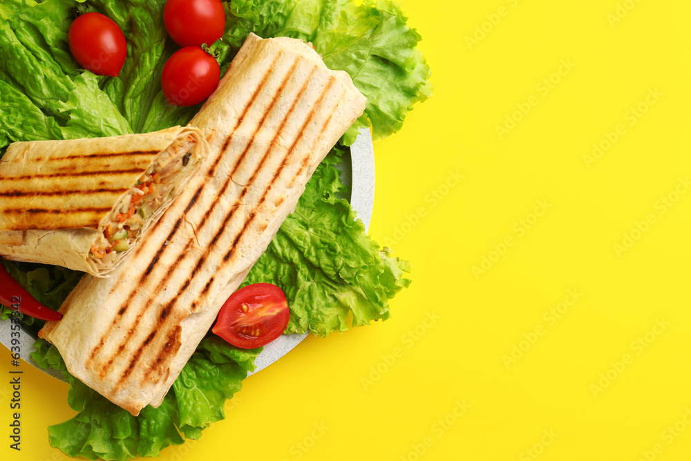 Plate of tasty shawarma with lettuce and tomatoes on yellow background