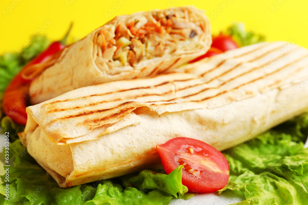 Tasty shawarma with lettuce and tomatoes on yellow background