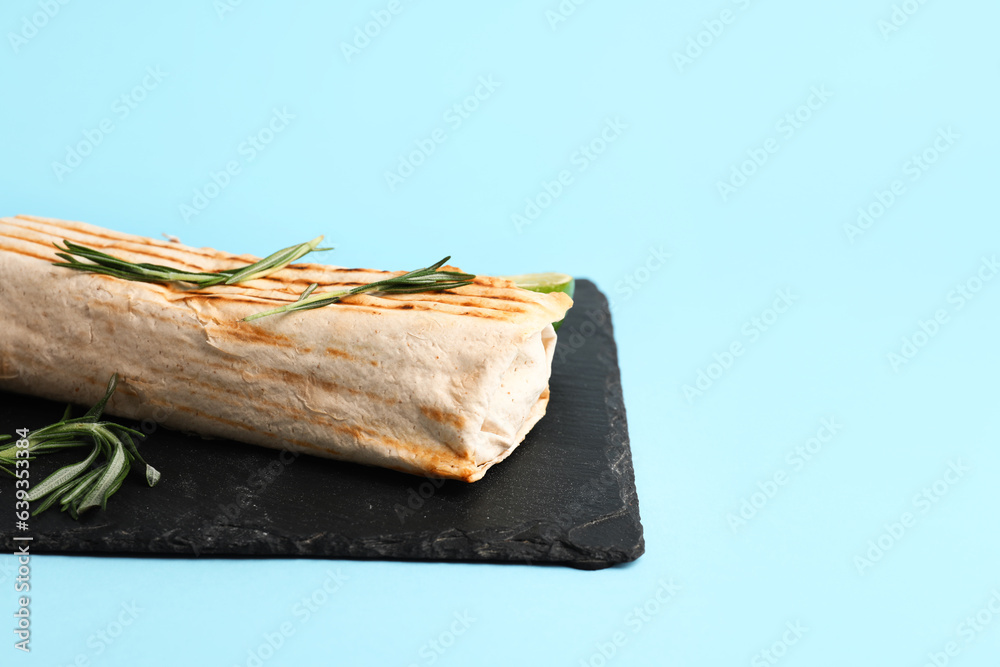 Board with tasty shawarma and rosemary on blue background