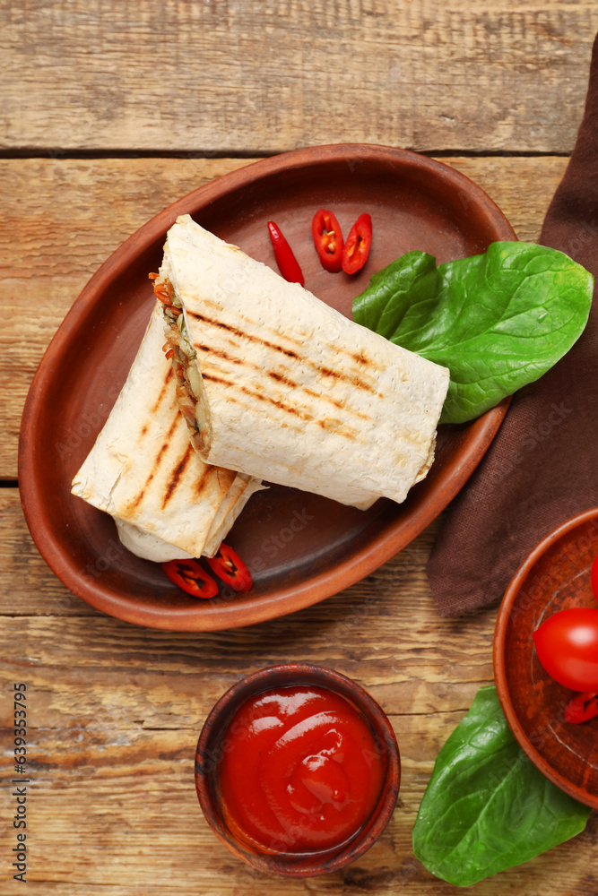 Plate with tasty shawarma and ketchup on wooden background