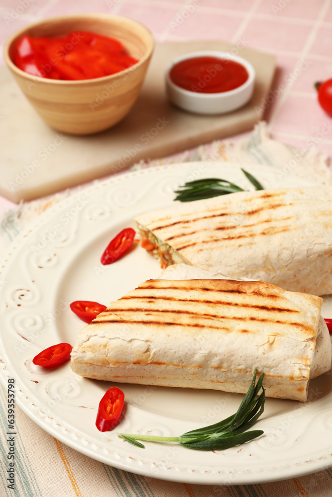 Plate with tasty shawarma and chilli on pink tile table