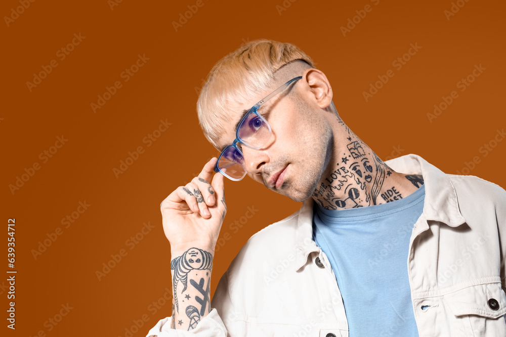 Young tattooed man in stylish eyeglasses on color background, closeup