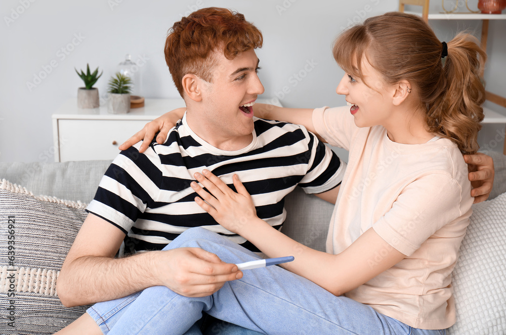 Happy young couple with pregnancy test at home