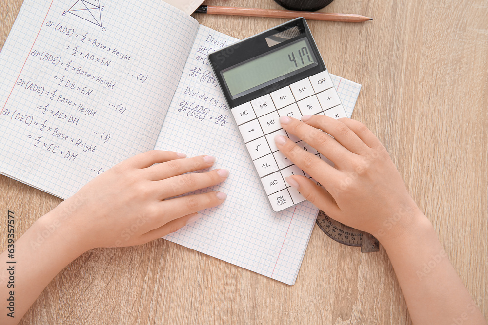 Woman working with calculator on wooden table, closeup