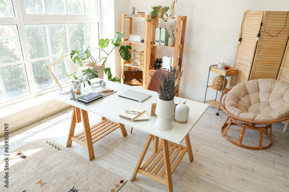 Modern workplace with laptop and lavender flowers in interior of office