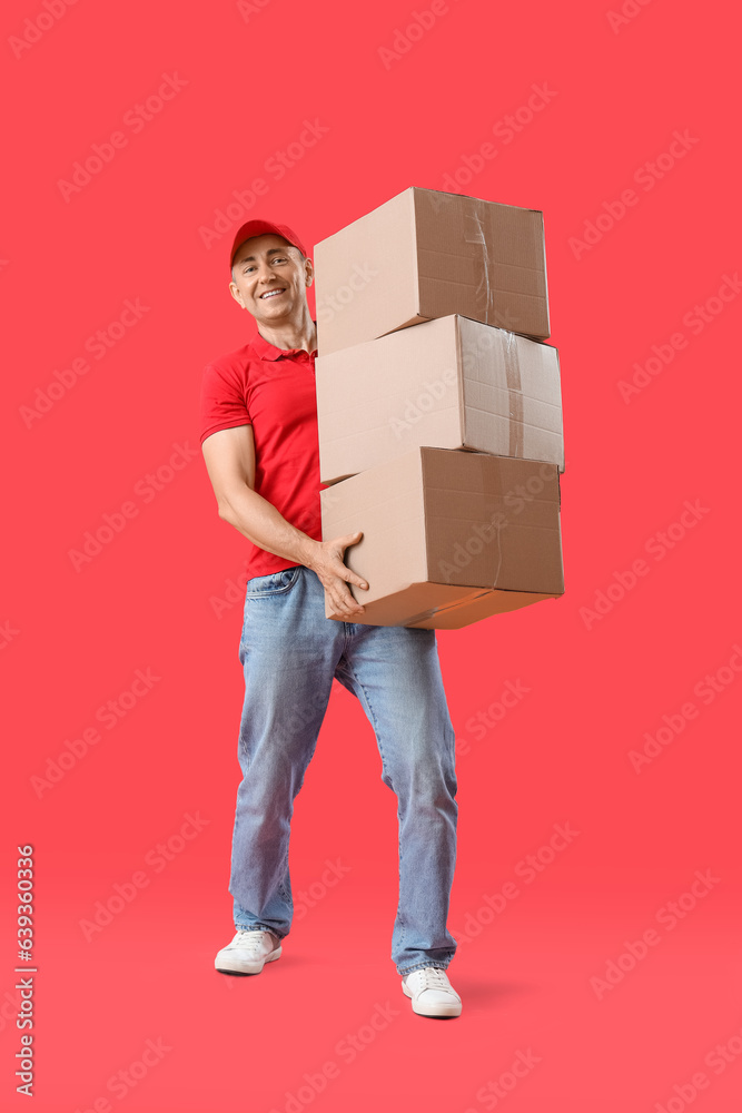 Mature courier with parcels on red background