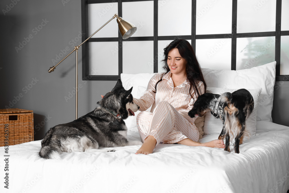 Young woman with cute dogs in bedroom