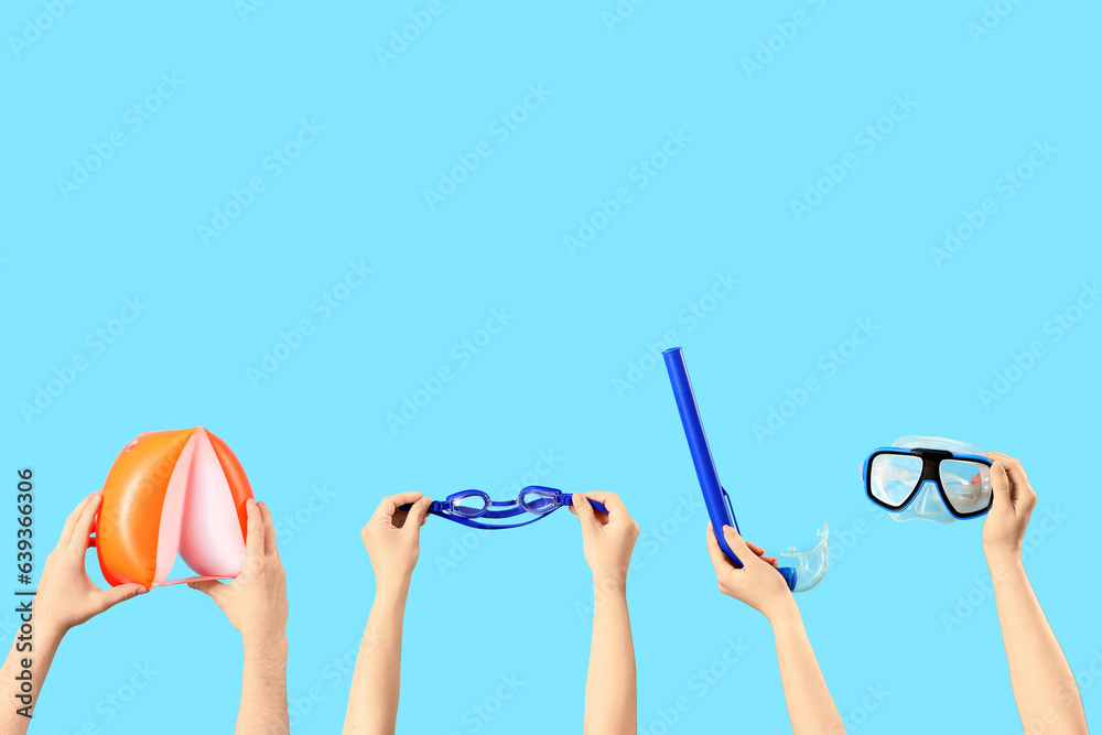 Female hands holding swimming equipment on blue background