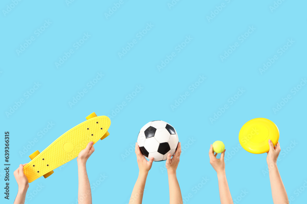 Female hands different sports equipment on blue background