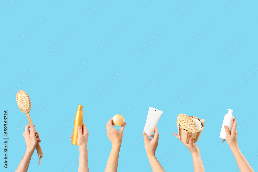 Female hands holding different cosmetic products on blue background