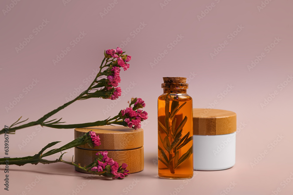 Different cosmetic products with beautiful flowers on lilac background