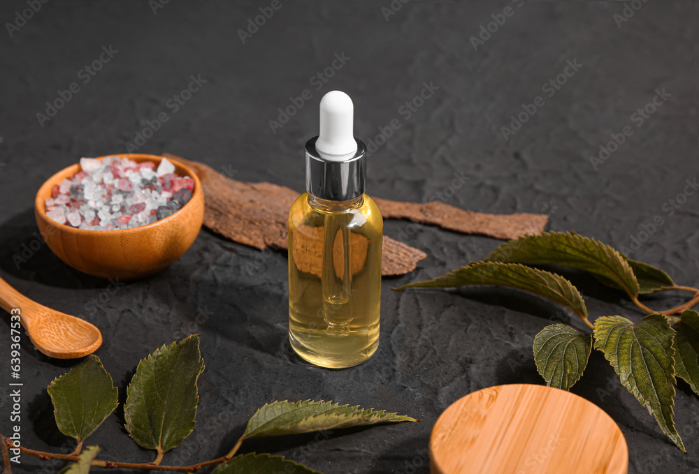 Bottle and jar of cosmetic products with sea salt on black background