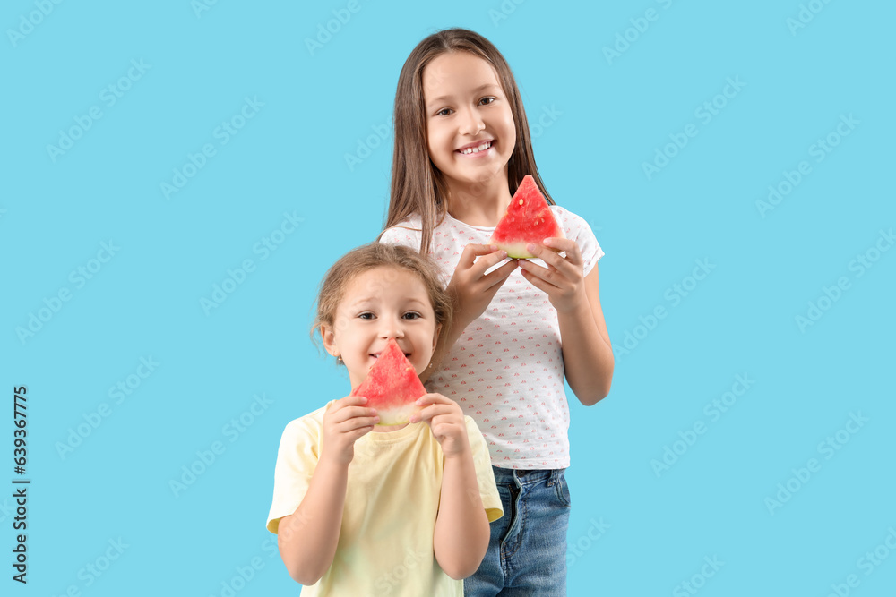 Little girls with slices of fresh watermelon on blue background