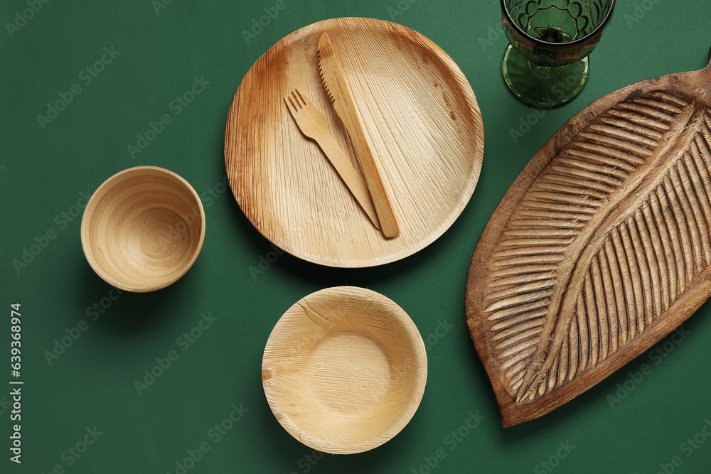 Different wooden tableware on green background