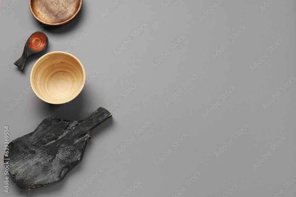 Different wooden tableware on grey background