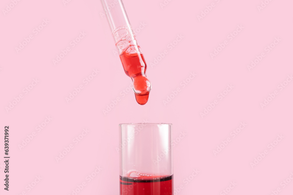 Pipette dripping sample into test tube on pink background, closeup