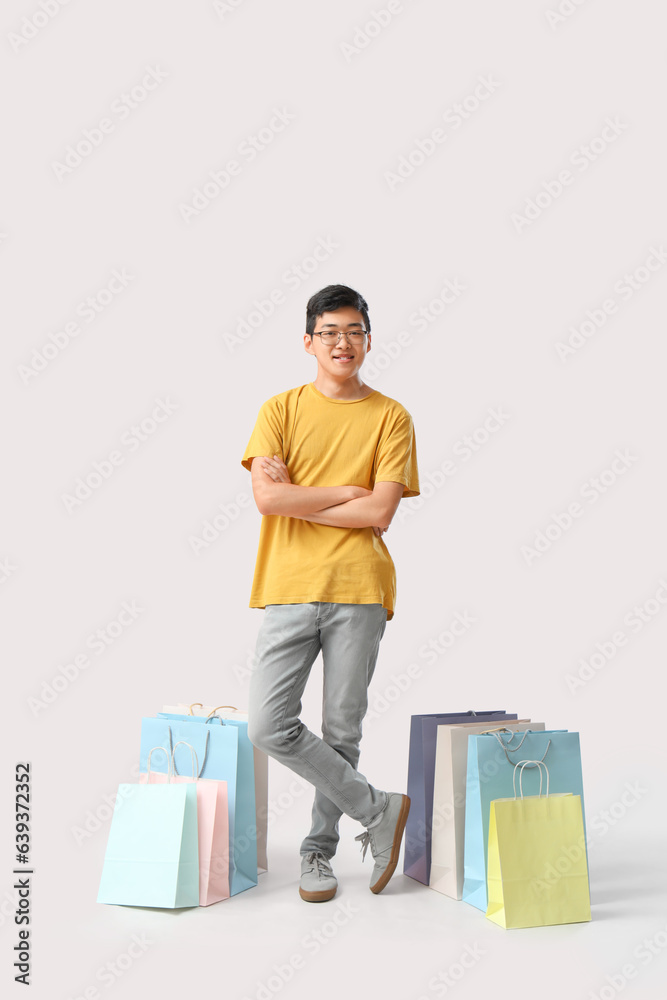 Young Asian man with shopping bags on white background