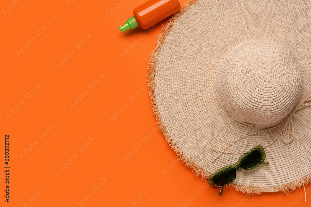 Stylish straw hat, sunglasses and bottle of sunscreen cream on color background