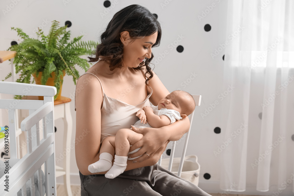 Young woman with her sleeping baby in bedroom