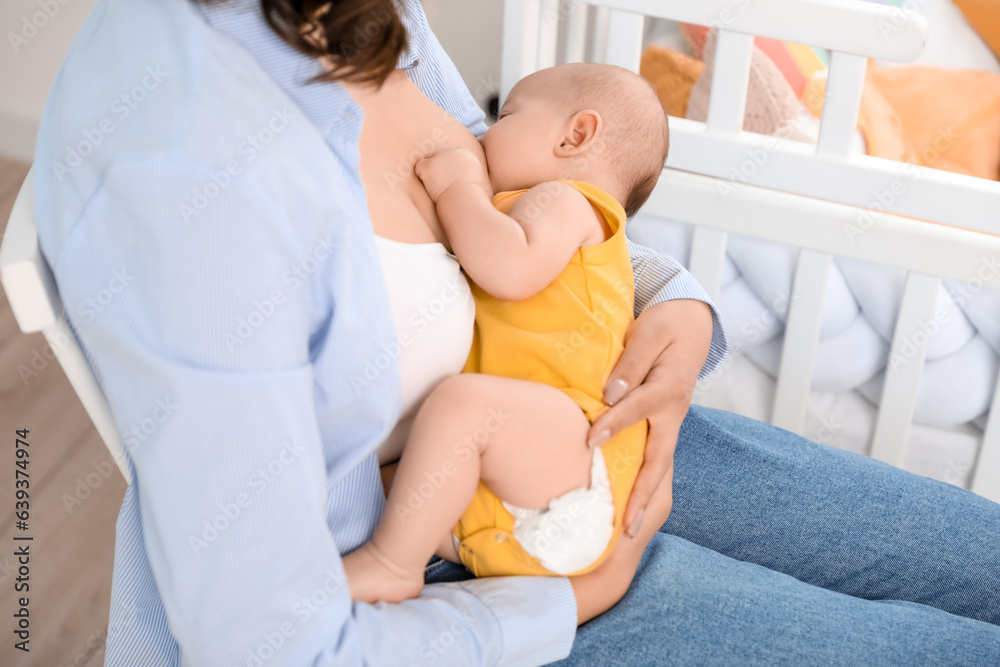 Young woman breastfeeding her baby in bedroom, closeup