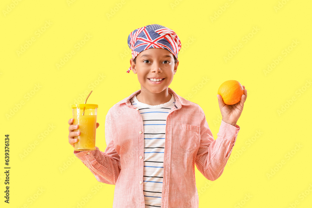 Little African-American boy with orange and cup of fresh juice on yellow background