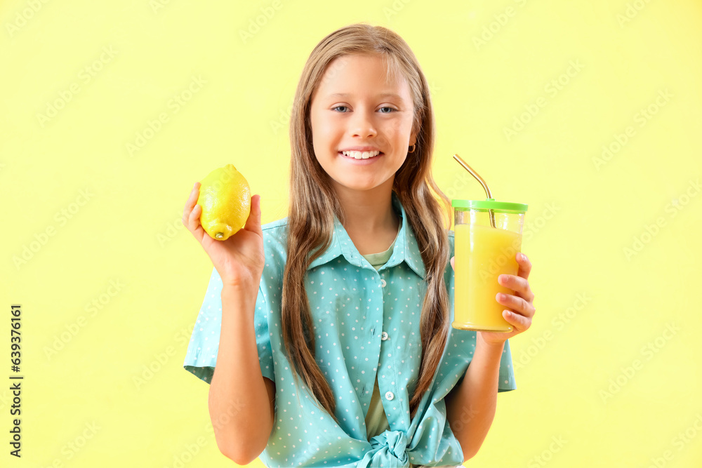 Little girl with lemon and glass of fresh juice on yellow background