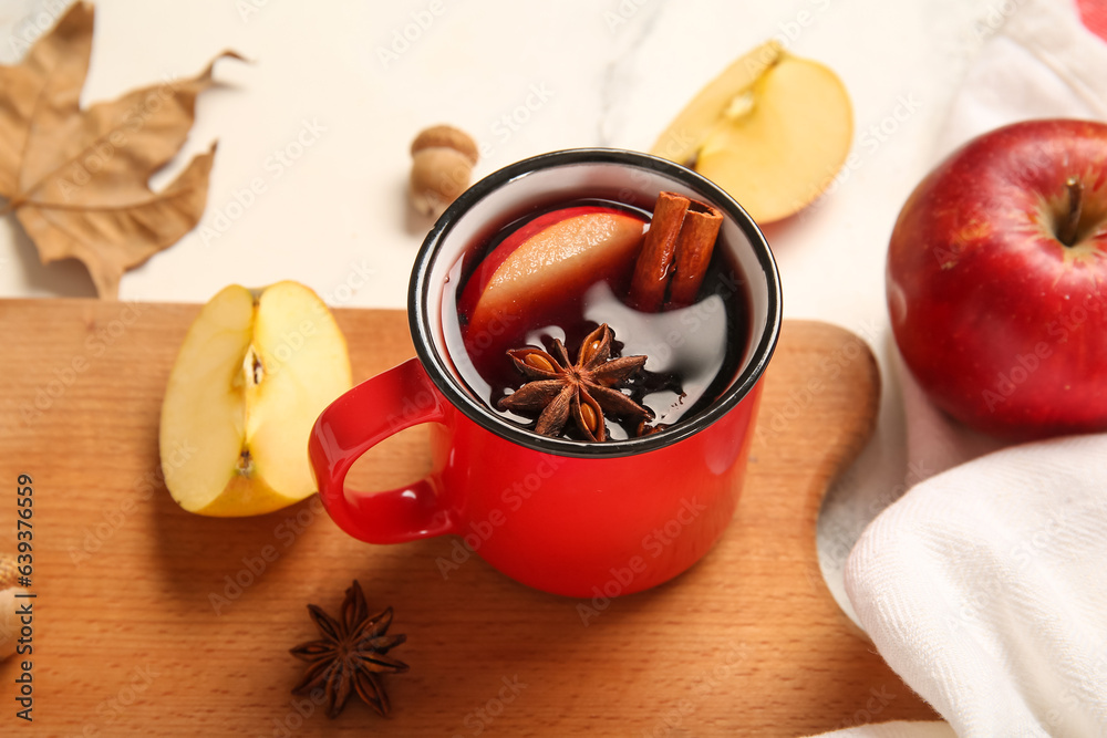 Cup of hot mulled wine with apple and cinnamon on white background