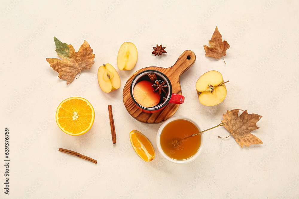 Cup of hot mulled wine with apple and bowl of honey on white background