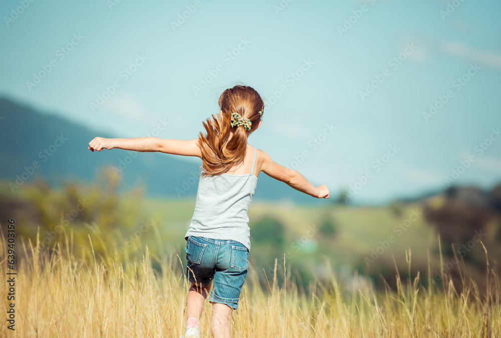 little girl runs through a beautiful meadow in the mountains. back view