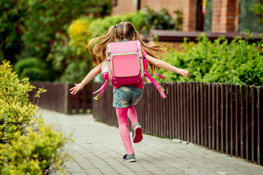 little girl with a backpack run to school. back view