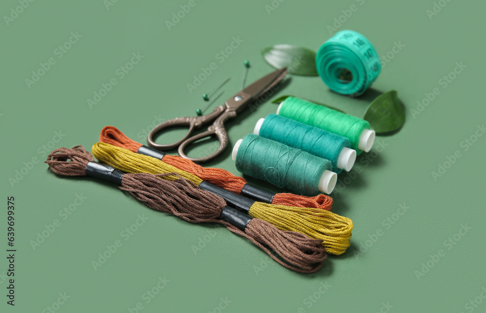 Set of different embroidery supplies on dark green background