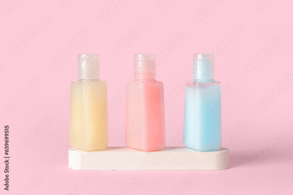 Plaster podium with bottles of cosmetic products on pink background