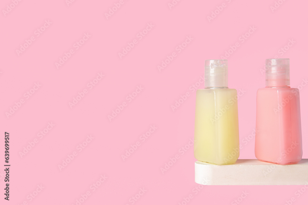 Plaster podium with bottles of cosmetic products on pink background