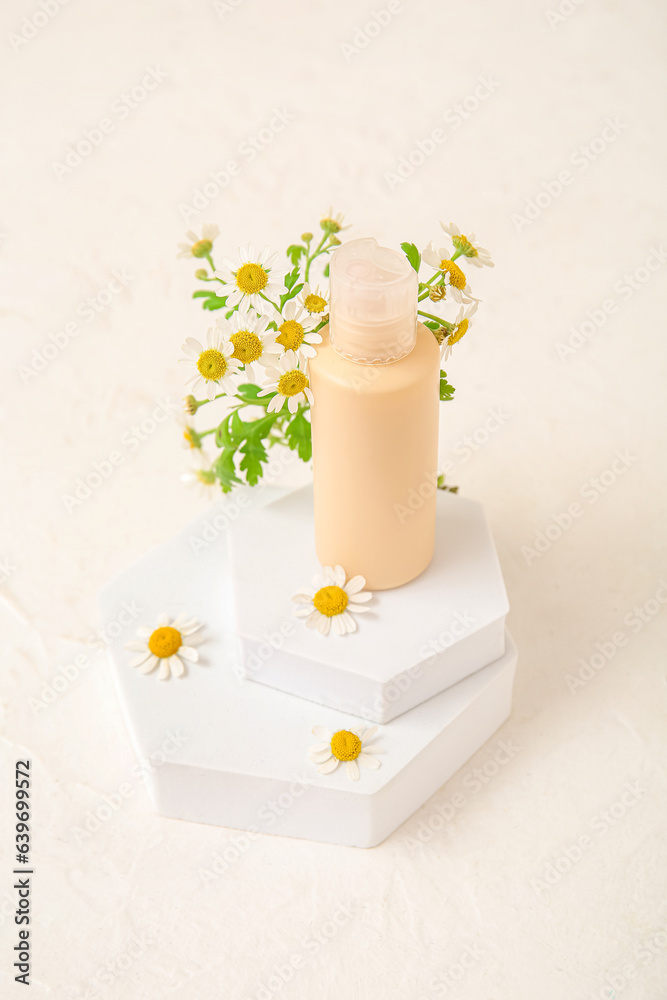 Composition with bottle of cosmetic product, plaster podiums and chamomile flowers on light backgrou